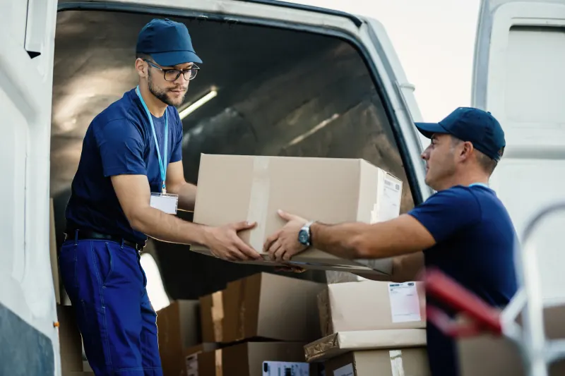 Two workers passing boxes out of a delivery van